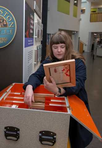 A woman looking through a box of artwork