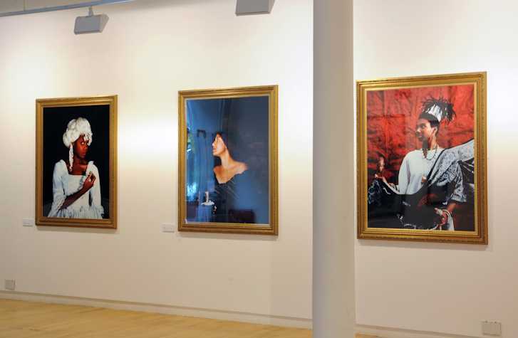 View in a gallery with 3 images on the walls of colourful framed photographs of Black creative women dressed as muses from Greek tradition, meant to celebrate the cultural accomplishments of Black women