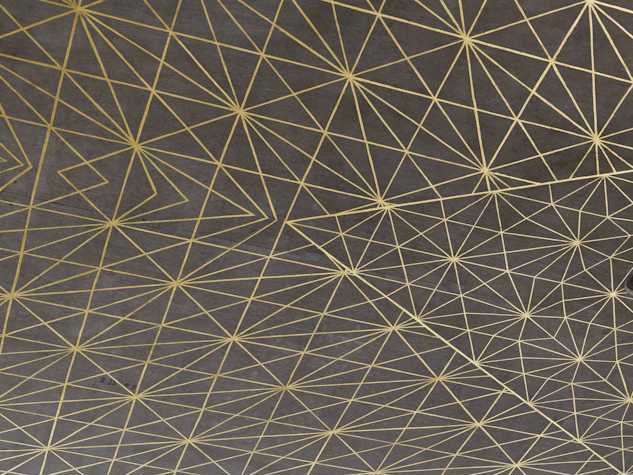 A close-up of a complex geometric pattern composed of various triangles which come together to form hexagons, rendered in gold leaf on a plain grey concrete ceiling.