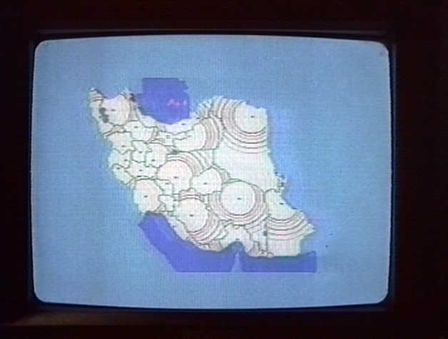 Video still of a television showing a graphic of Iran covered in dots emanating circular signals. 