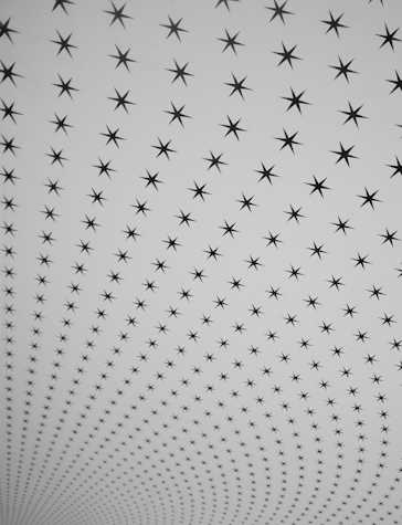 A photograph showing a wall painting of a repeating pattern of black six-pointed stars on a curved white ceiling. The stars diminish in scale from the top of the image to the bottom as the room recedes